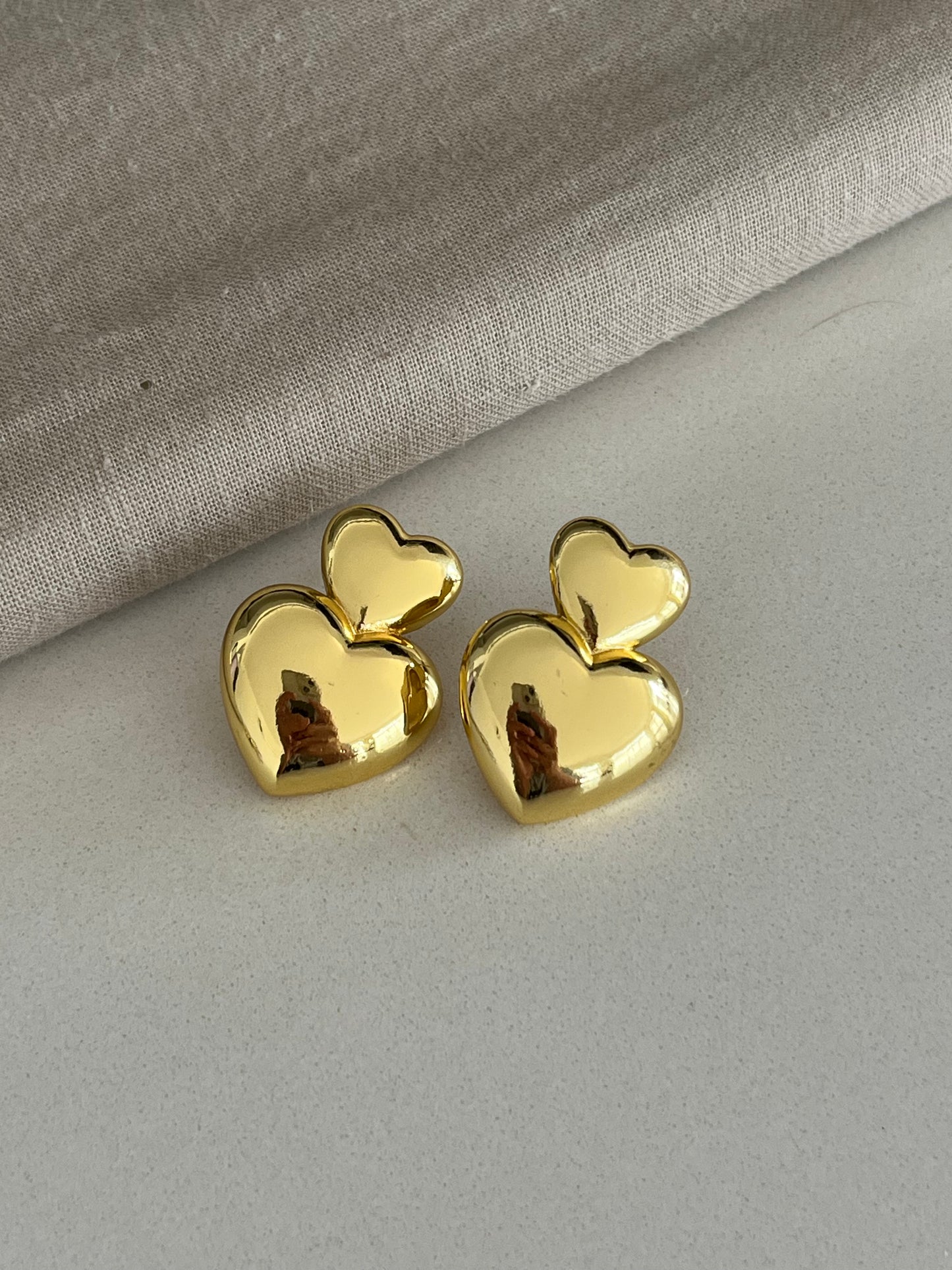 Aretes dorados con dos corazones unidos tipo topo